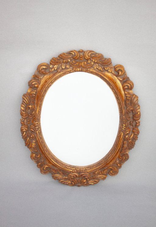 Oval mirror, gilded and carved from wood. Exclusive vintage mirror, handmade by expert artisans.