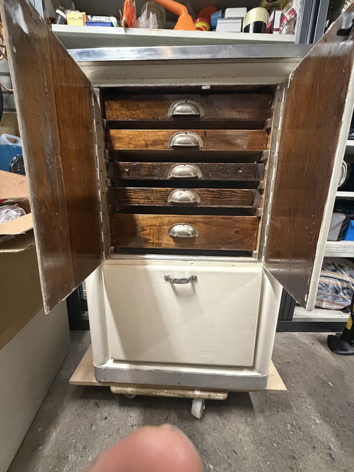 Armoire de médecin vintage sur roulettes avec tiroirs en bois.