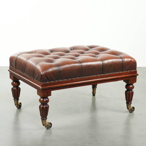 Grote bruine rundleren chesterfield hocker in Engelse stijl met sierlijke poten en messing wieltjes