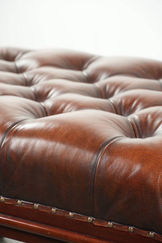 Image 1 of Grote bruine rundleren chesterfield hocker in Engelse stijl met sierlijke poten en messing wieltjes
