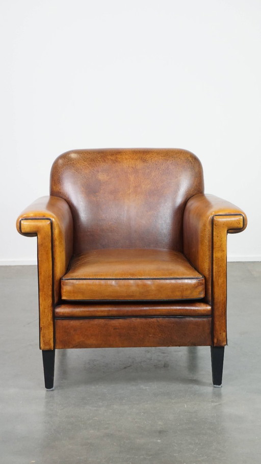 Sillón de diseño Art Déco en buen estado, con un acabado elegante y ribetes negros.
