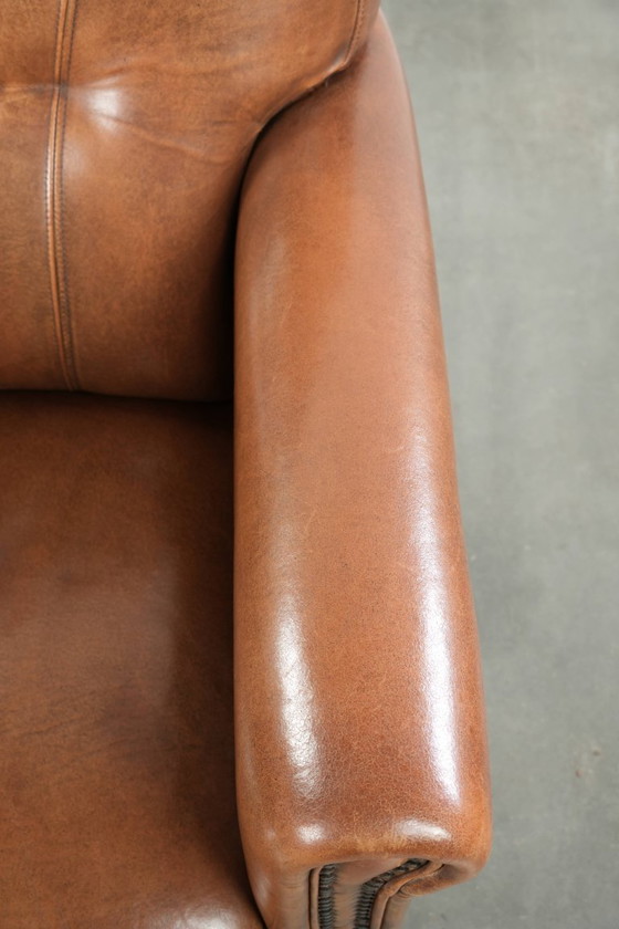 Image 1 of Fauteuil en bon état, en peau de mouton avec une finition raffinée et des clous décoratifs.