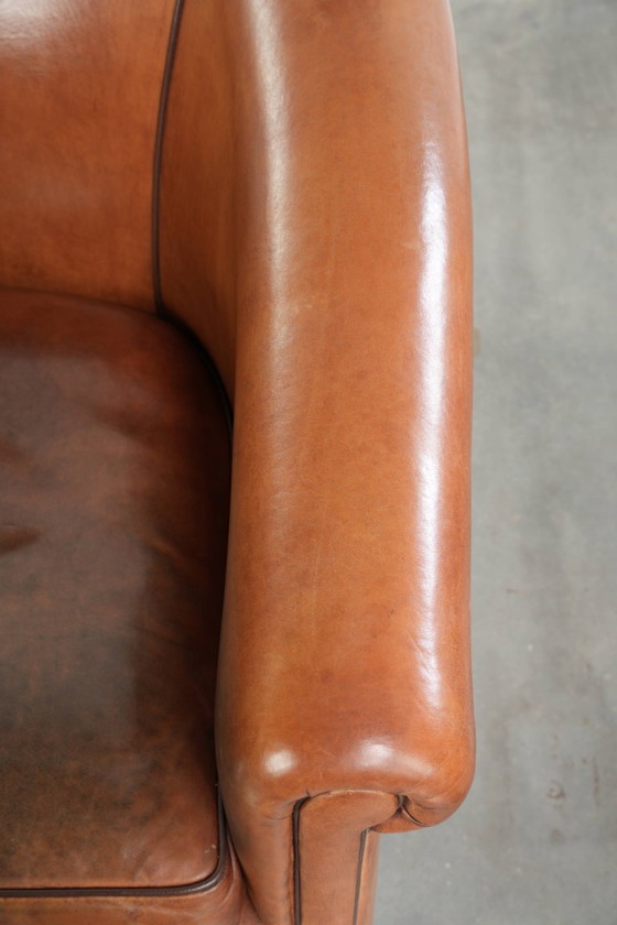 Image 1 of Vintage schapenleren clubfauteuil met een warme kleurstelling en afgewerkt met zwarte biezen