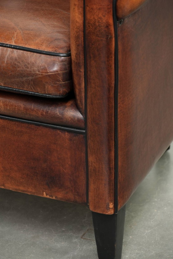 Image 1 of Mooie en karaktervolle schapenleren clubfauteuil met mooie diepe warme kleuren, zwarte biezen en een comfortabele zit