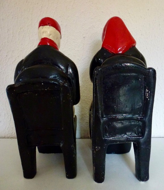 Image 1 of A set of decorative bookends depicting an elderly couple sitting on chairs.