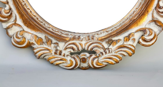 Image 1 of Oval mirror, gilded and carved from wood. Decorated and distressed with scrolls and leaves. Exclusively handmade by artisans.