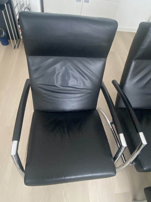 Dos sillones Leolux y un puf Helical con tapizado de piel Wapiti negra y estructura cromada.