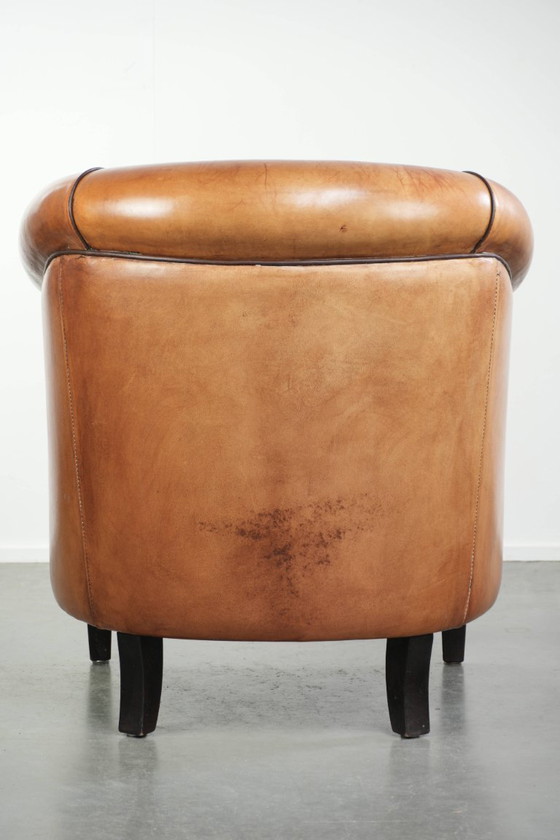 Image 1 of Vintage schapenleren clubfauteuil met een warme kleurstelling en afgewerkt met zwarte biezen