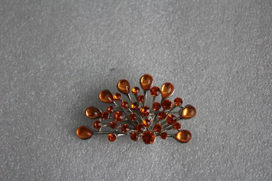 Image 1 of Gebogen broche met honingkleurige glazen steentjes op een zilverkleurig metalen frame, vintage uit de jaren 80.