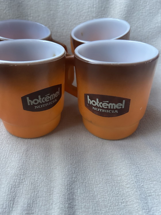 Image 1 of Dit is een set vintage Hotcemel Nutricia kopjes of mokken van oranje opaalglas met een kleurverloop.