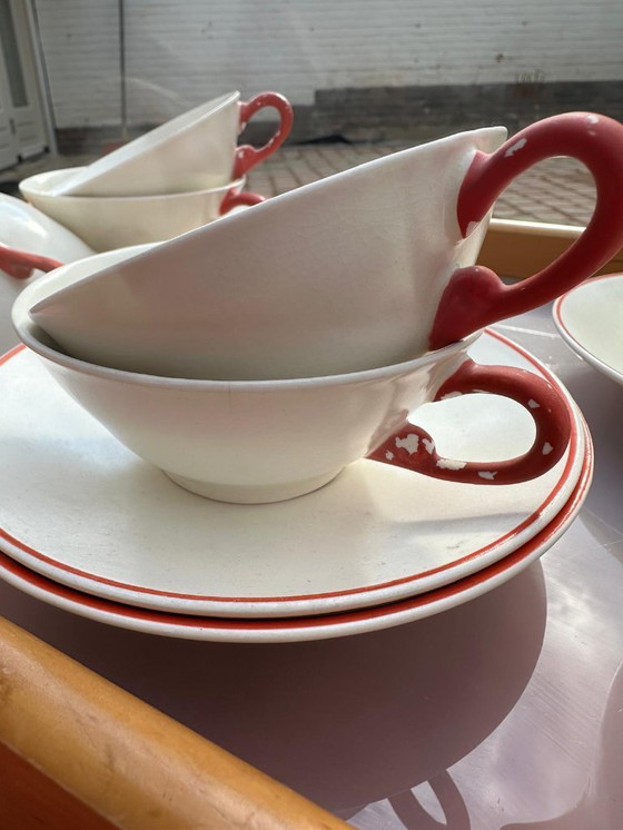 Image 1 of Set van 7 aardewerken kopjes, 5 schotels en 1 melkkan. Gemerkt met afbeelding van een springend hert en het woord 'Holland'.    