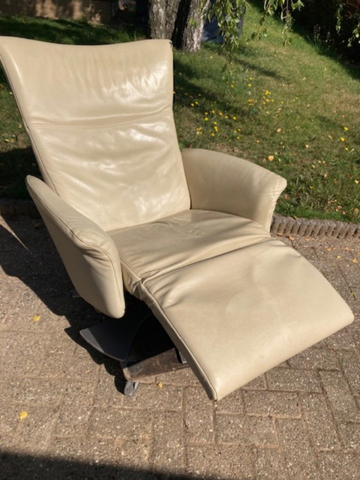 A swivel recliner armchair by Rolf Benz. Cream colored with matte chrome base. Used.
