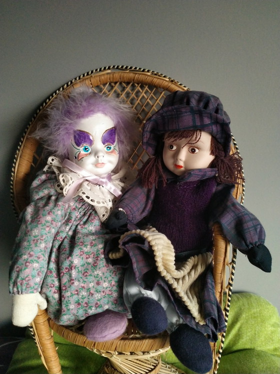 Image 1 of Deux véritables poupées en porcelaine sur une chaise en osier originale
