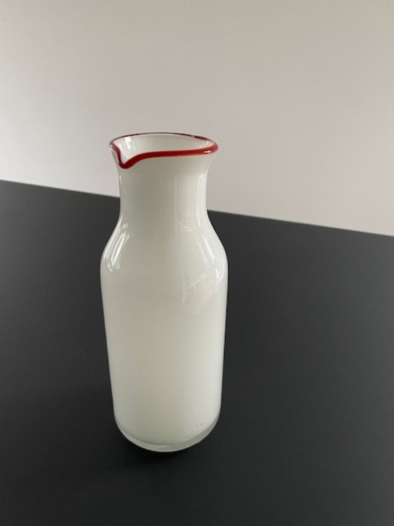 Image 1 of Caraffa dal design scandinavo in vetro bianco con bordo rosso.