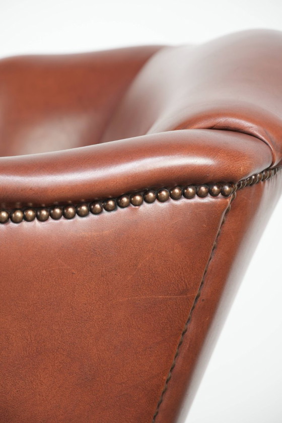 Image 1 of Comoda poltrona a orecchioni in pelle bovina color cognac in stile inglese.