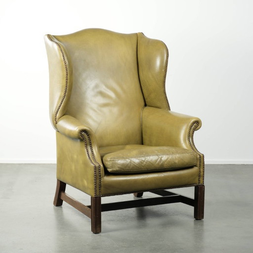 Fauteuil à oreilles ancien et élégant en cuir de vachette vert, de style classique de maison de campagne anglaise.