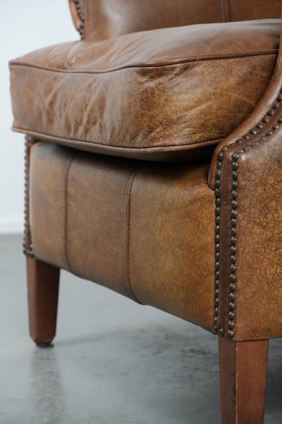 Image 1 of Tijdloze cognac kleurige oorfauteuil in Engelse stijl gemaakt van rundleer afgewerkt met siernagels