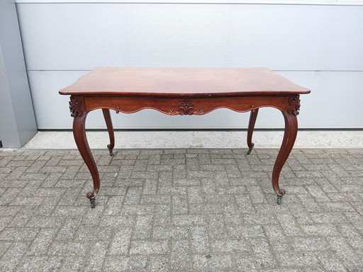 The antique dining table is made of mahogany and has a Louis XV style.