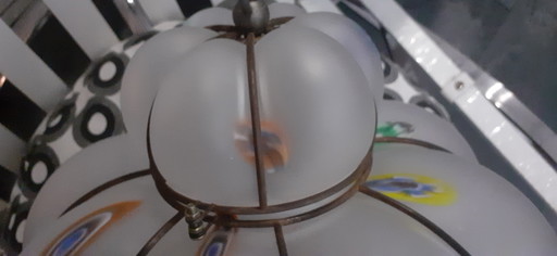 Lámpara colgante de vidrio lechoso con acentos de color.