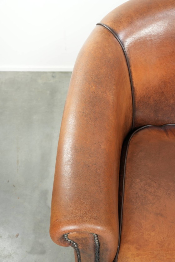 Image 1 of Schapenleren clubfauteuil met een mooie patina en een verfijnde afwerking met zwarte biezen