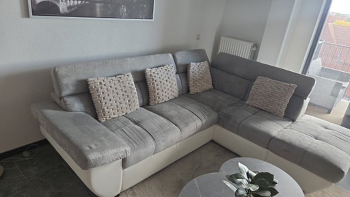 Sofá esquinero moderno blanco/gris con aspecto de piel y tela.