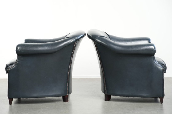 Image 1 of 2 comode poltrone club in pelle bovina blu scuro dal design unico e senza tempo.