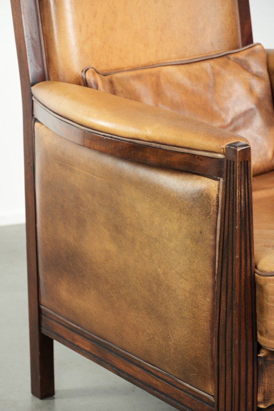Image 1 of Cómodo sillón de diseño Art Déco en color coñac, fabricado en piel de oveja combinada con madera y con respaldo alto.