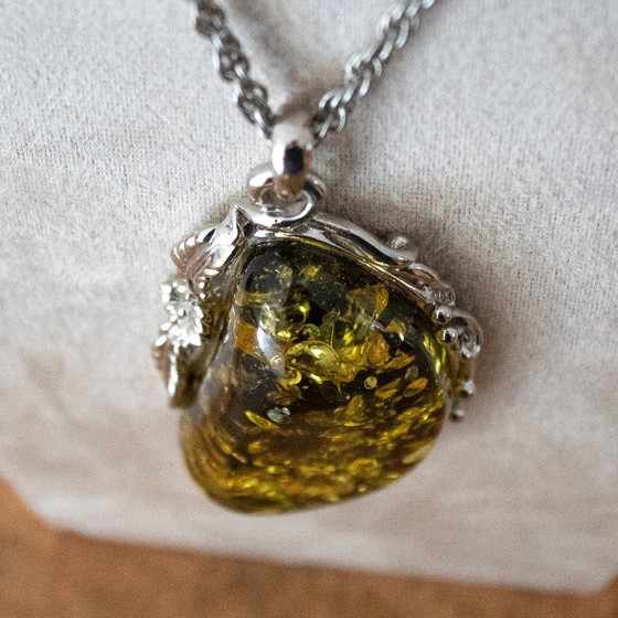 Image 1 of Grande ciondolo in ambra baltica verde: incastonato in metallo color argento con decorazioni floreali.