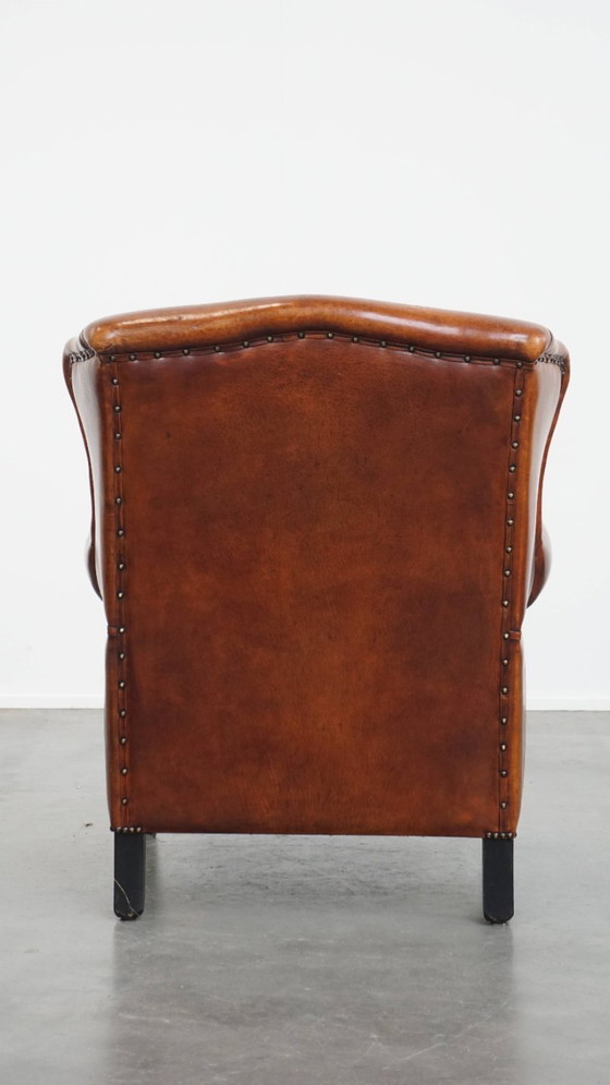 Image 1 of Comfortabele schapenleren oorfauteuil met een prachtige warme kleurstelling en een afwerking met stiksels en zwarte biezen