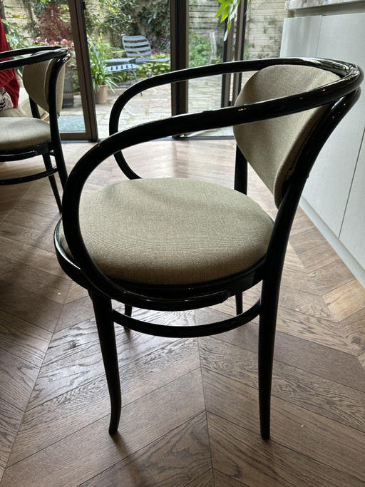 4 sillas Thonet 209 con estructura de madera curvada negra y asiento tapizado.