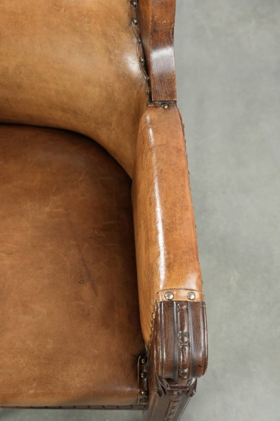 Image 1 of Antique armchair of sheepskin and wood with decorative nails and beautiful woodwork