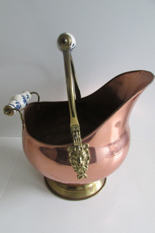 Cubo de carbón de cobre antiguo con forma de casco y cabezas de león