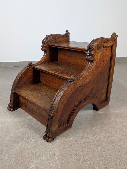 Ornate wooden step stool with carved faces