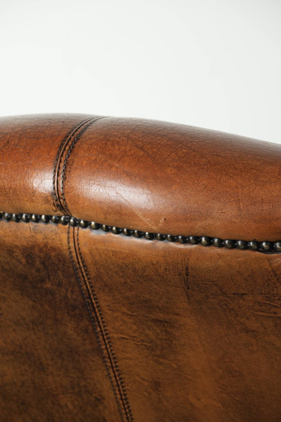 Image 1 of Comfortabele oorfauteuil gemaakt van schapenleer afgewerkt met siernagels en een karaktervolle uitstraling in Engelse stijl