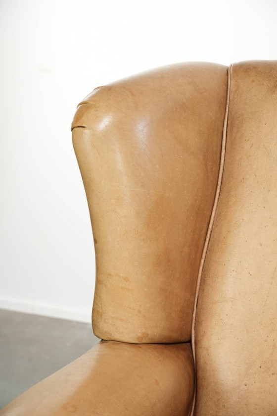 Image 1 of Dos hermosos sillones orejeros de piel de vaca clara con un estilo inglés atemporal y gran comodidad.