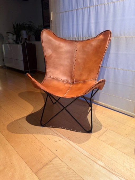 Vlinderstoel in leder https://www.maisonsdumonde.com/BE/nl/p/camelkleurige-leren-vlinderstoel-santiago-121926.htm?utm_source=goo