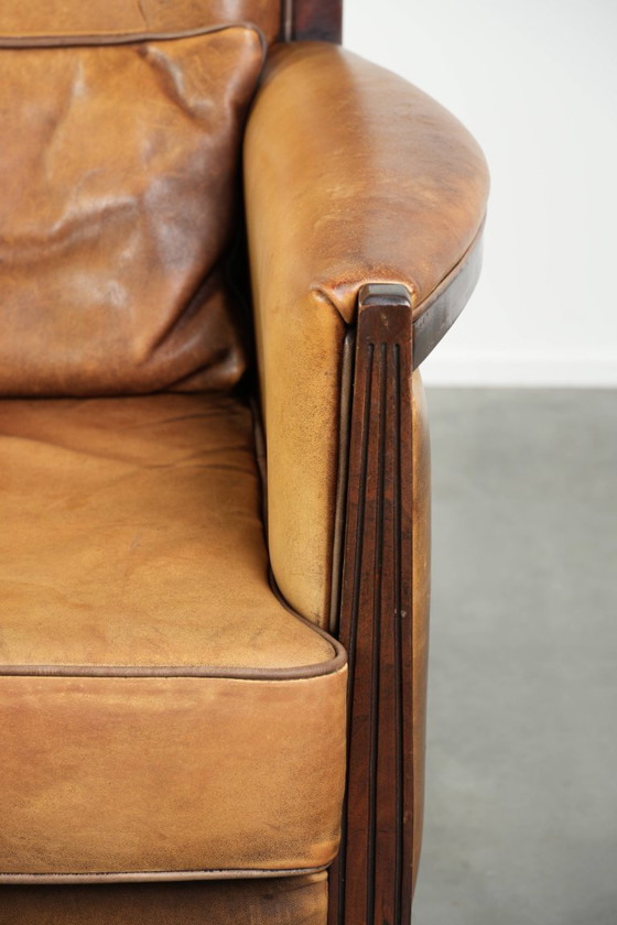 Image 1 of Cómodo sillón de diseño Art Déco en color coñac, fabricado en piel de oveja combinada con madera y con respaldo alto.
