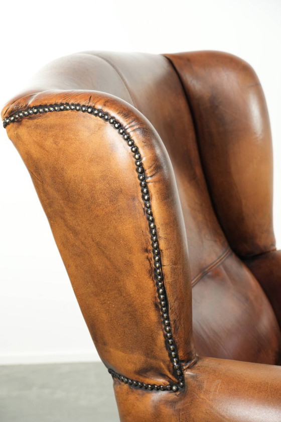 Image 1 of Comfortabele oorfauteuil gemaakt van schapenleer afgewerkt met siernagels en een karaktervolle uitstraling in Engelse stijl