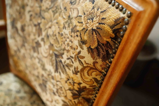 Image 1 of Vintage salonfauteuil met bloemenpatroon op de bekleding en sierlijke armleuningen.