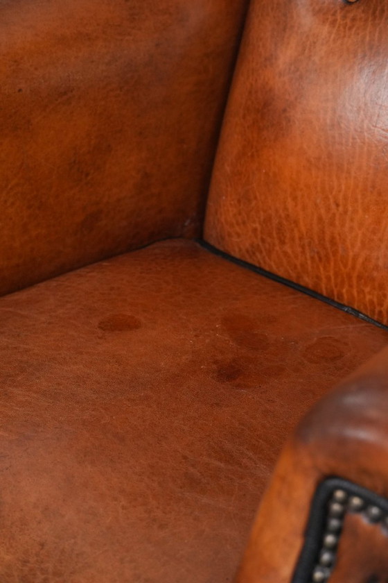 Image 1 of Grote oorfauteuil gemaakt van schapenleer met zwarte biezen en siernagels