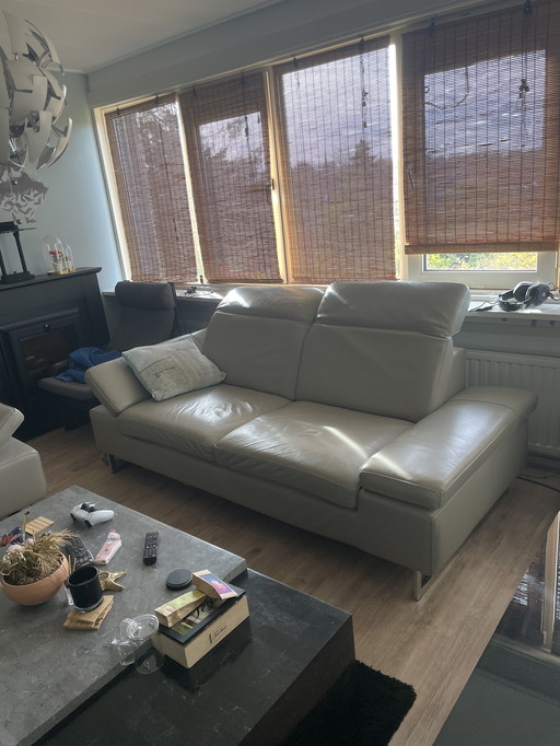 Grijze leren bank met verstelbare hoofd-arm leuningen.