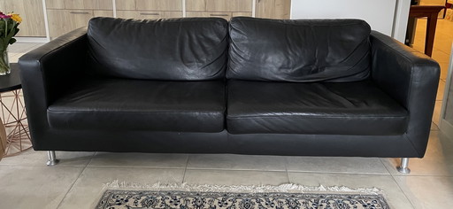 Black leather three-seater sofa.
