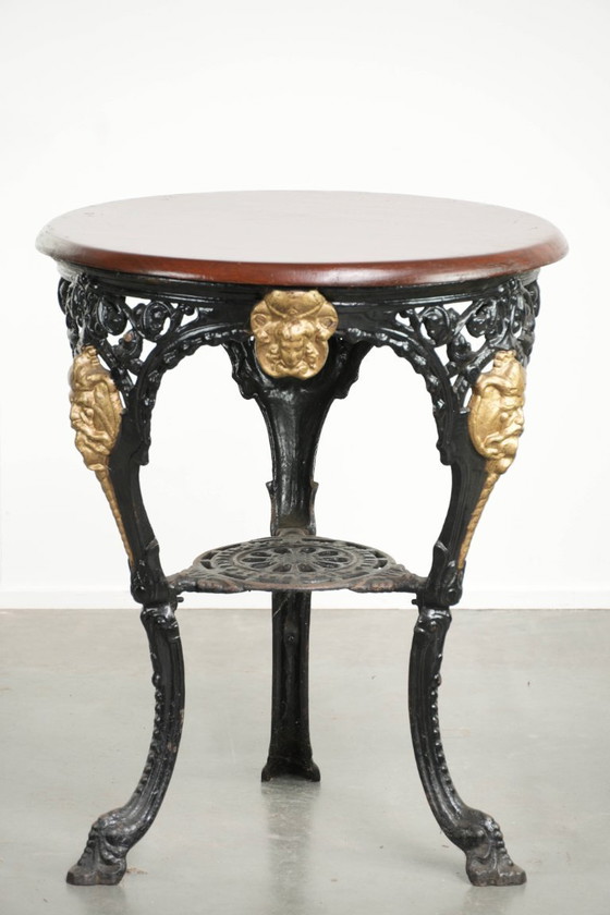 Image 1 of Antieke Engelse bistro/ bijzettafel met een gietijzeren onderstel uit begin 20e eeuw en een massief houten tafelblad