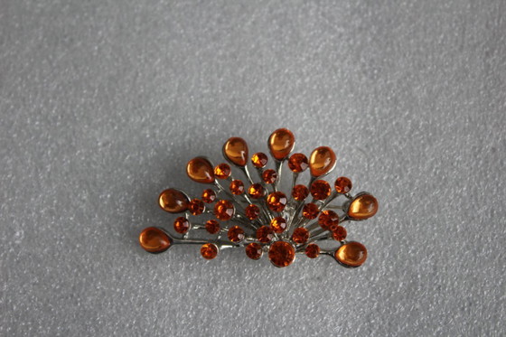 Image 1 of Gebogen broche met honingkleurige glazen steentjes op een zilverkleurig metalen frame, vintage uit de jaren 80.