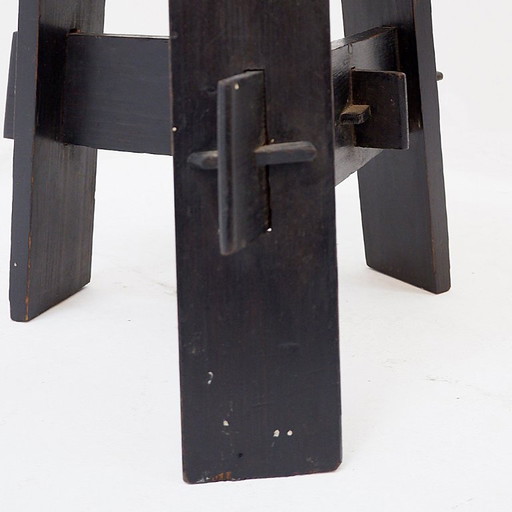 Vintage driepootkruk van zwart gebeitst hout met pen-en-gatverbindingen.