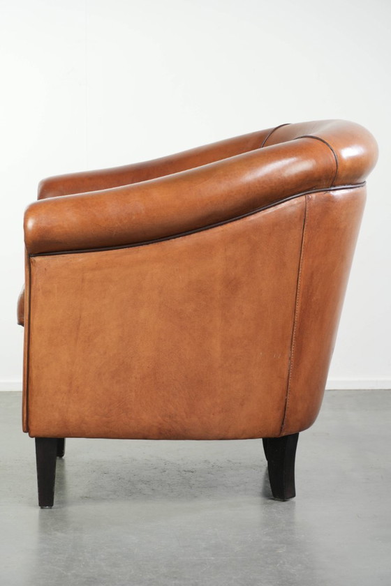 Image 1 of Vintage schapenleren clubfauteuil met een warme kleurstelling en afgewerkt met zwarte biezen