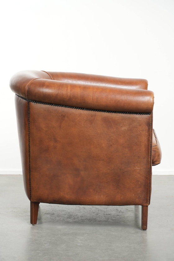 Image 1 of Poltrona club in montone color cognac caldo, rifinita con borchie decorative.