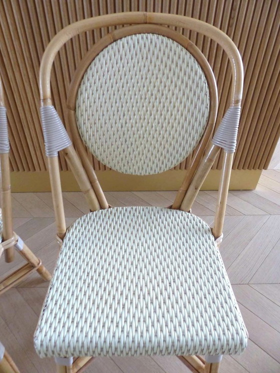 Image 1 of Een paar Parijse bistrostolen van Maison Louis Drucker in licht Manila-rotan.
