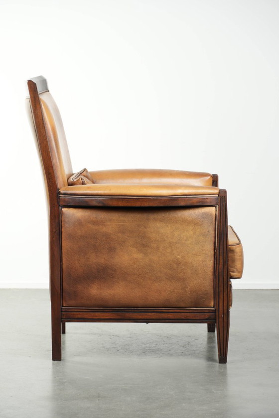 Image 1 of Cómodo sillón de diseño Art Déco en color coñac, fabricado en piel de oveja combinada con madera y con respaldo alto.