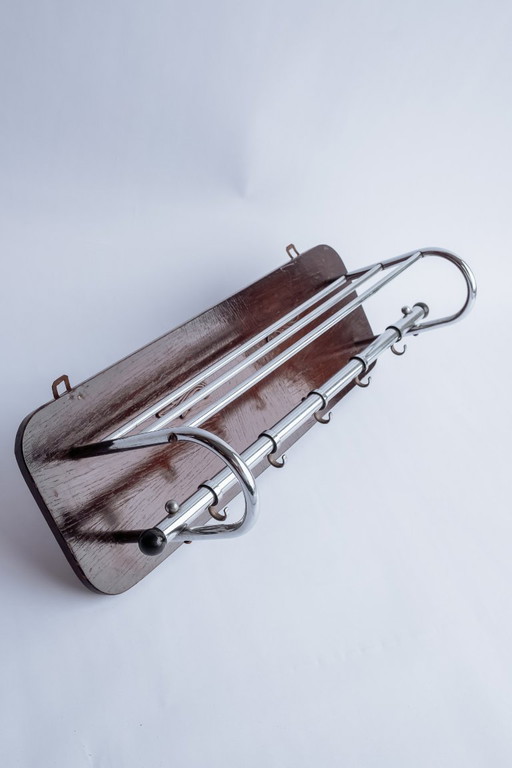 Perchero antiguo de madera con estante para sombreros y ganchos cromados.